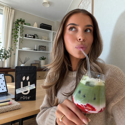 Дівчина п'є Strawberry Matcha Protein, поруч пакет rüte